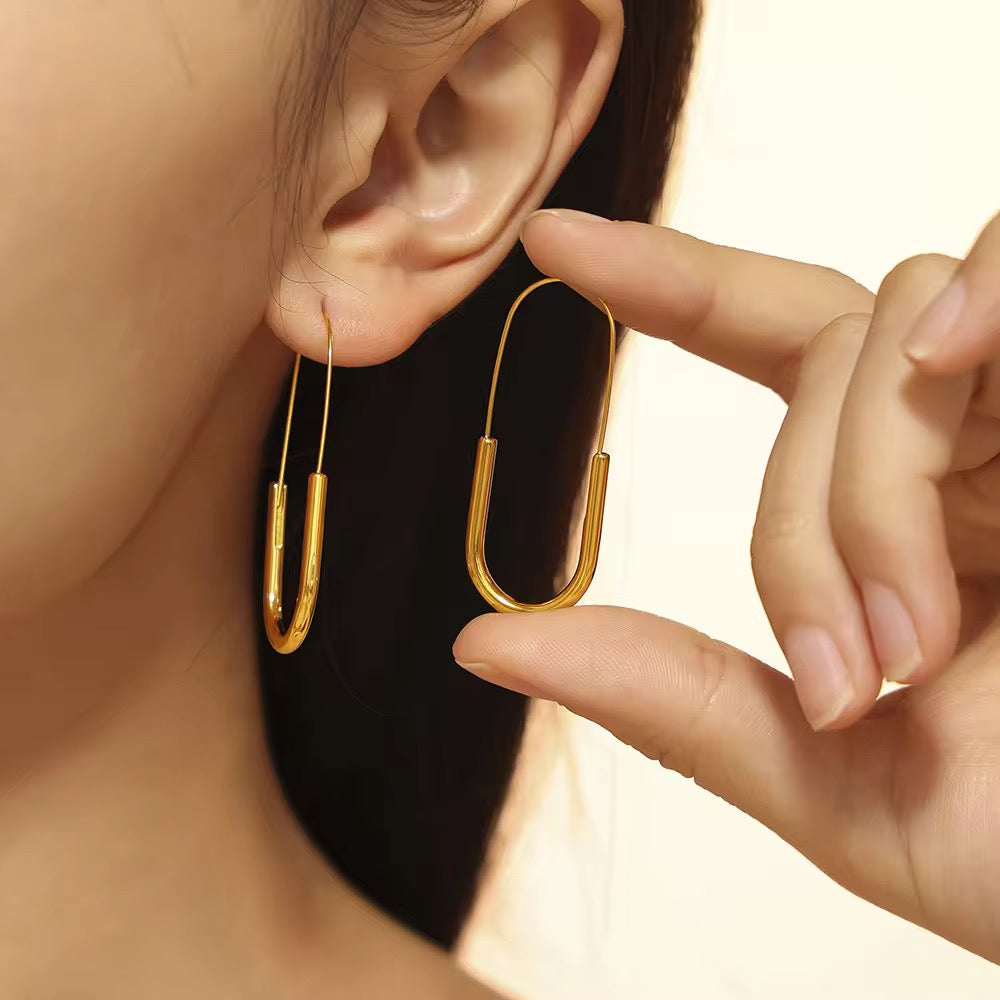 Gold hoop earrings being worn and adjusted by a hand