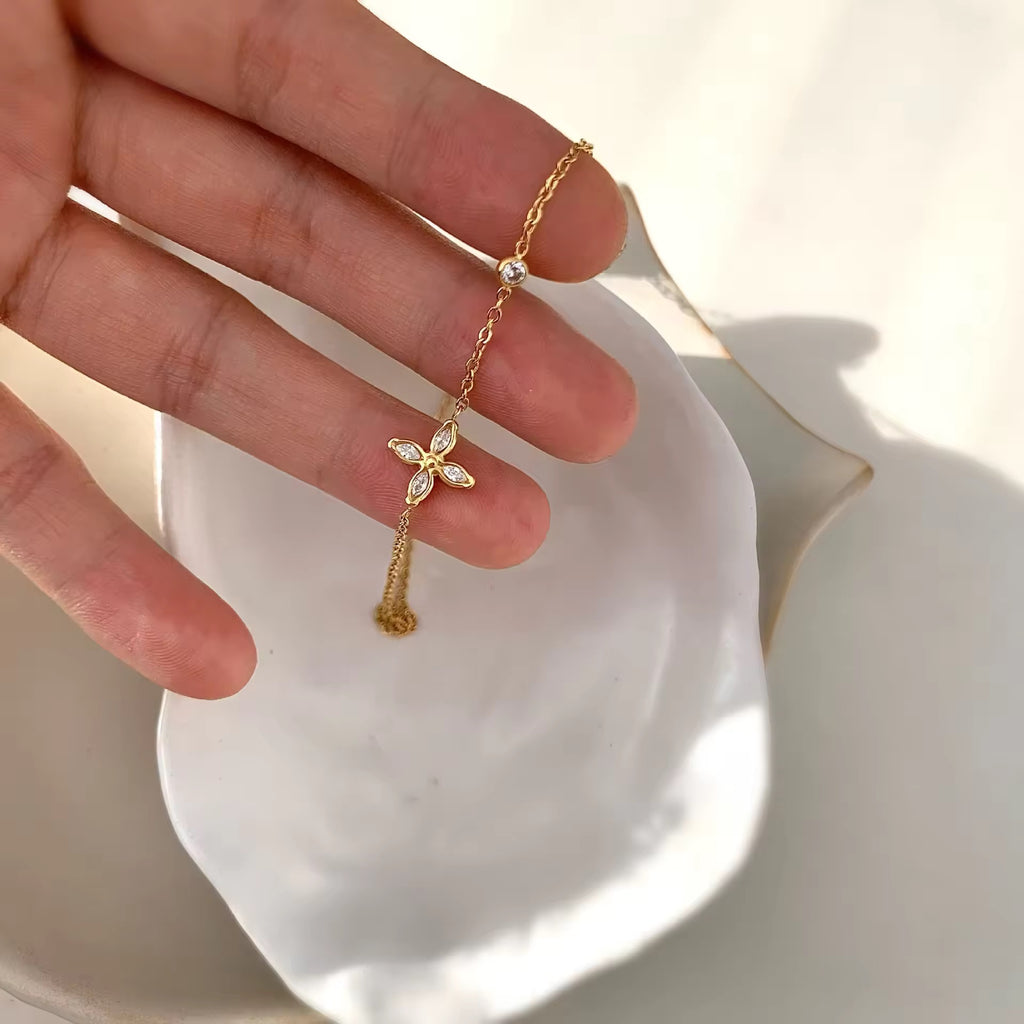 Gold necklace with a butterfly pendant held by a hand on a white dish.