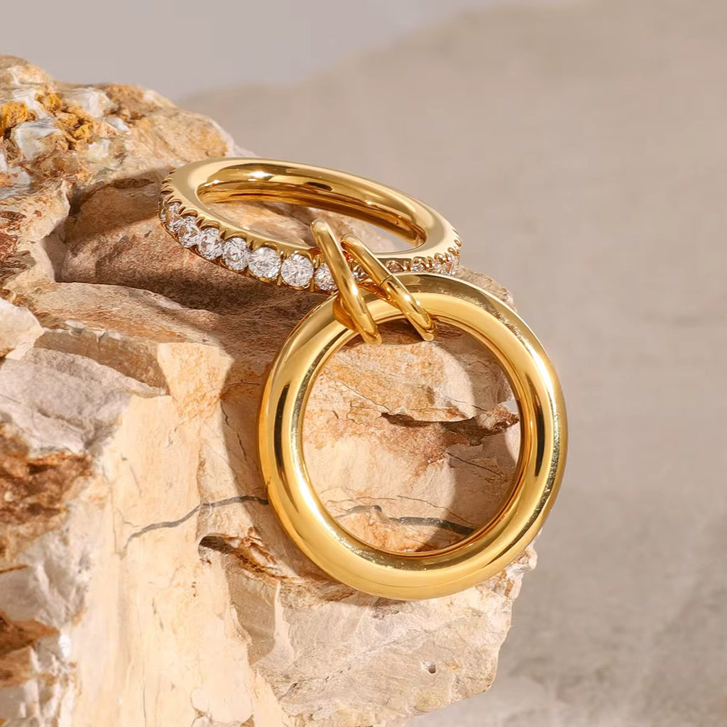 Two gold rings with diamond accents on a textured stone surface