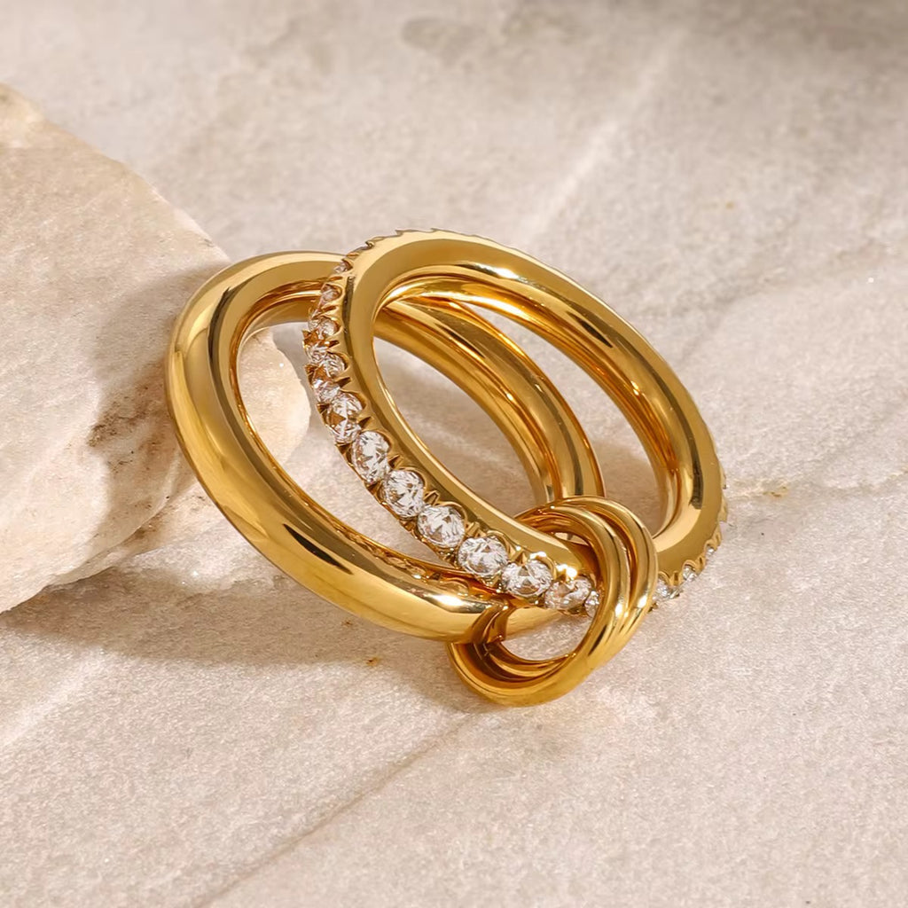 Gold ring with diamond accents on a beige stone background