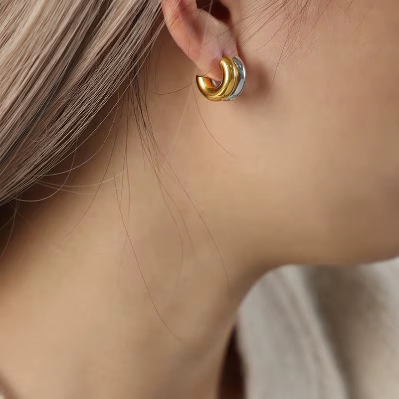 Close-up of a gold hoop earring worn by a person with light skin and blonde hair.