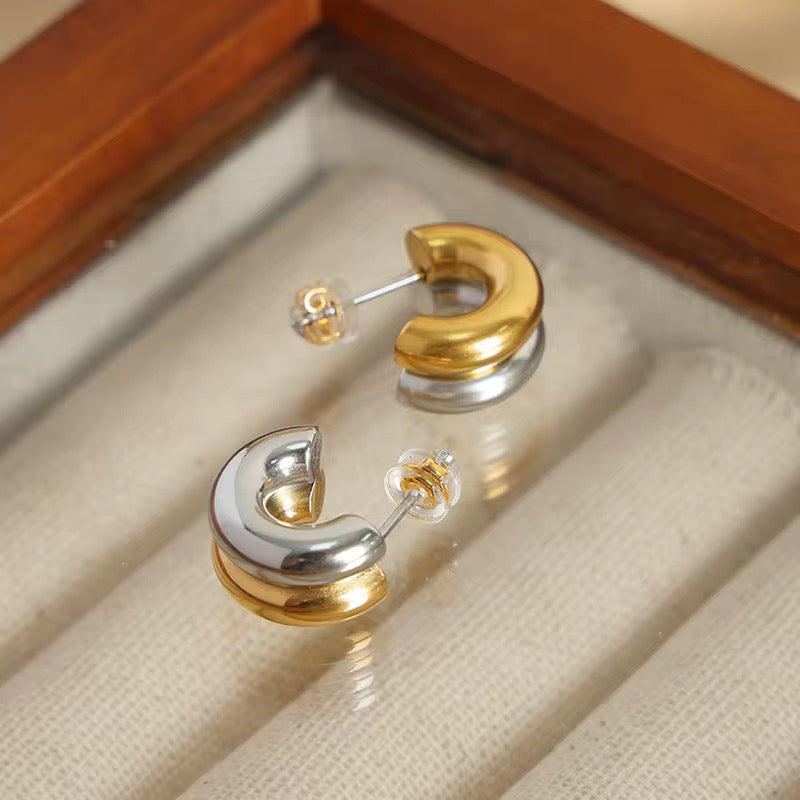Gold and silver earrings on a soft fabric surface