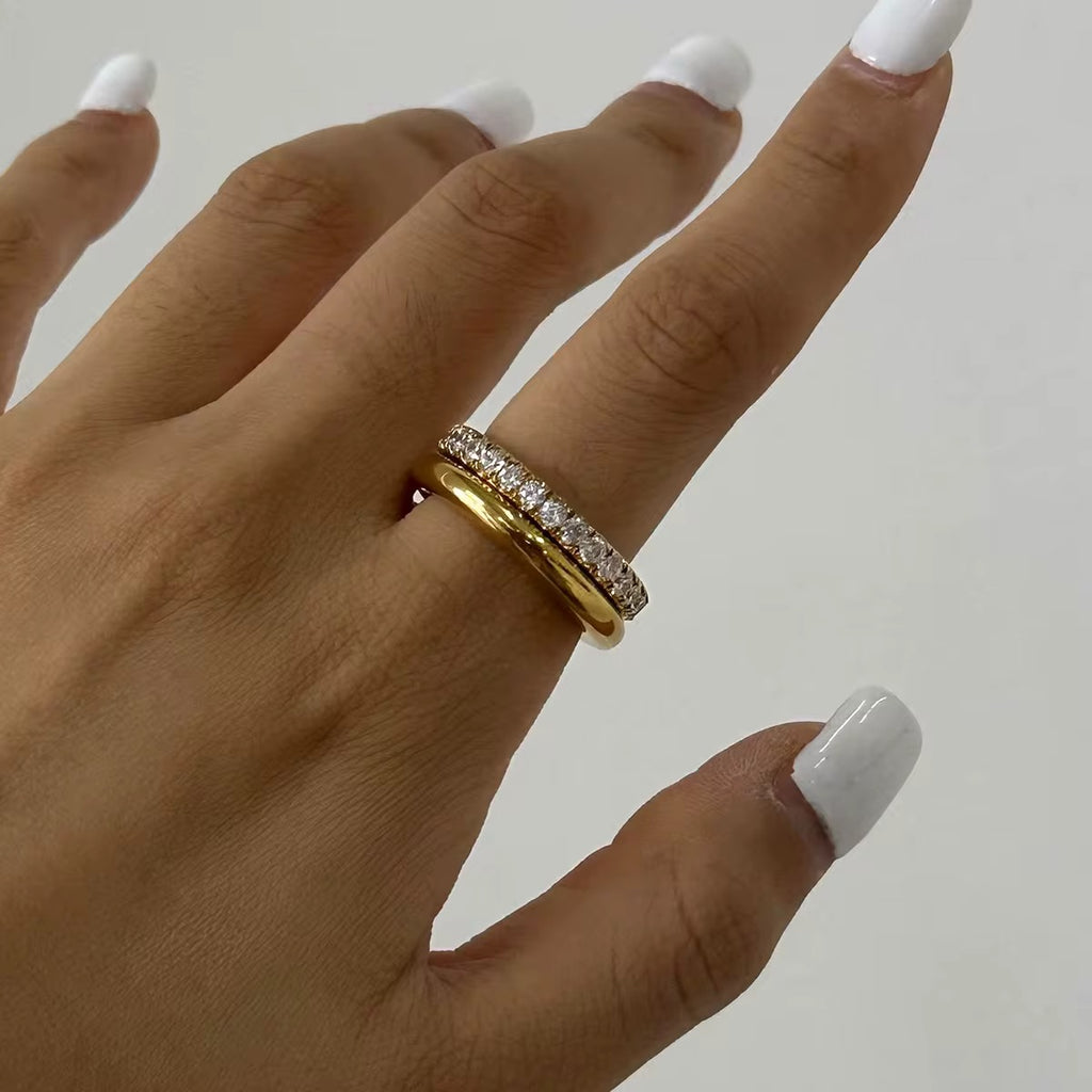 Hand wearing a gold ring with a white background