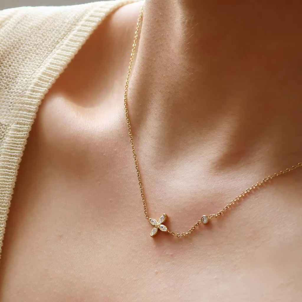 Gold necklace with a flower pendant on a person's neck