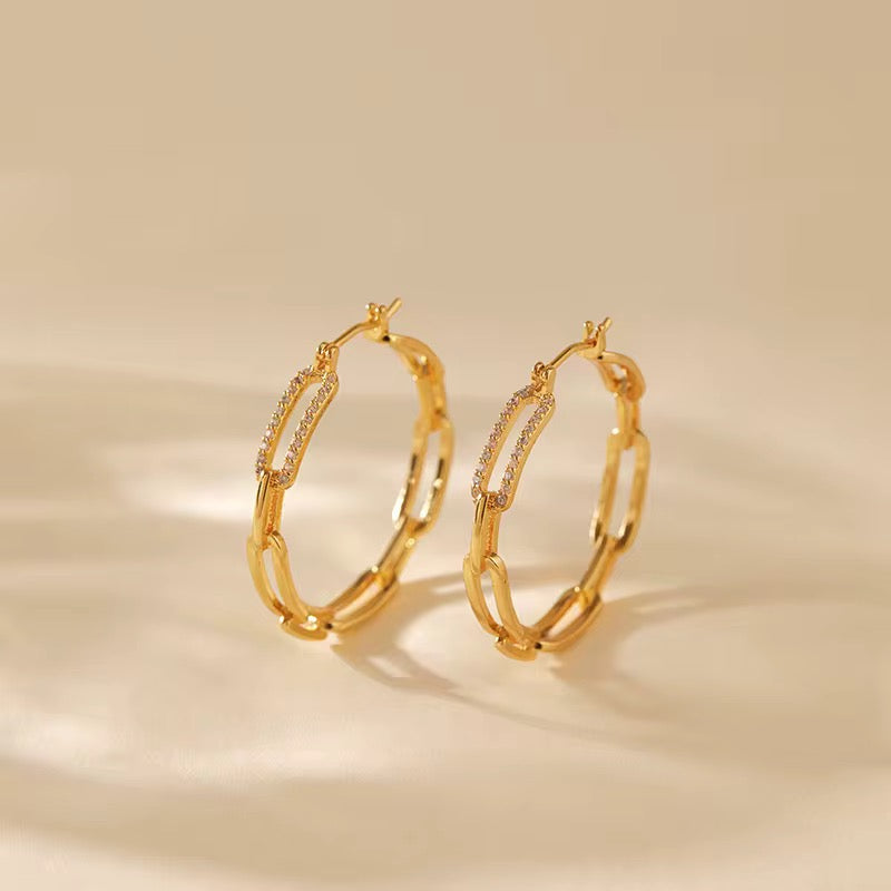 Gold hoop earrings with chain links on a beige background