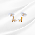 Pair of white flower-shaped earrings with gold centers on a light gray background