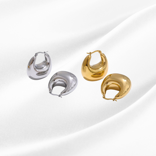 Pair of silver hoop earrings and gold crescent moon-shaped earrings on a light background