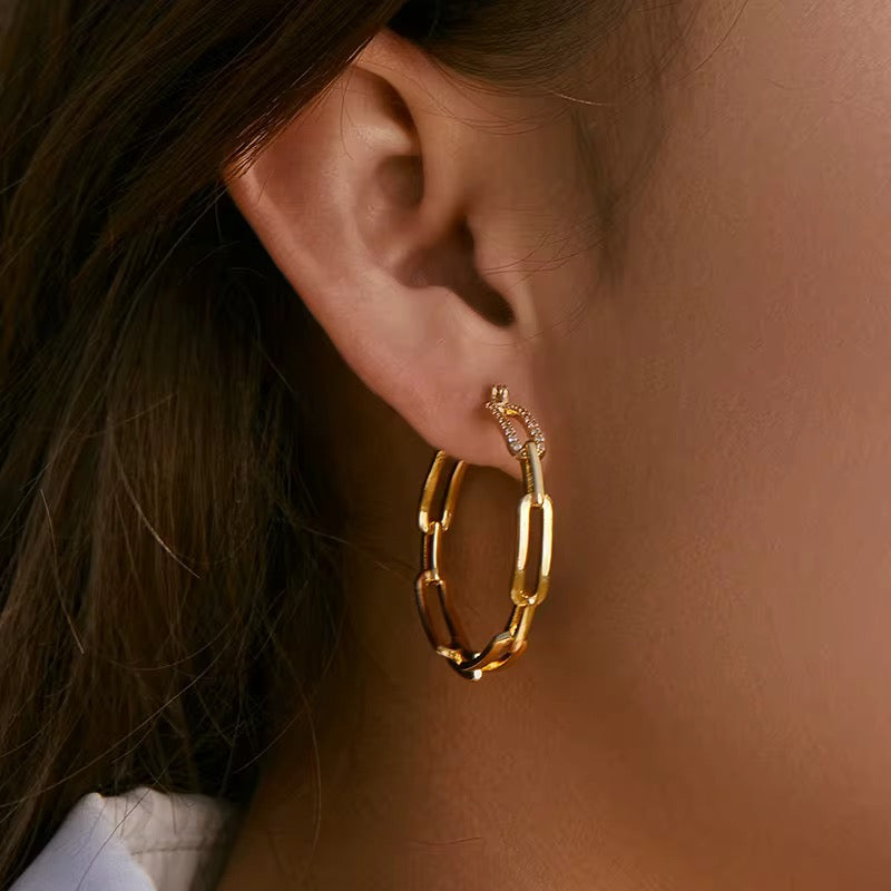 Gold hoop earrings worn by a person with dark hair.