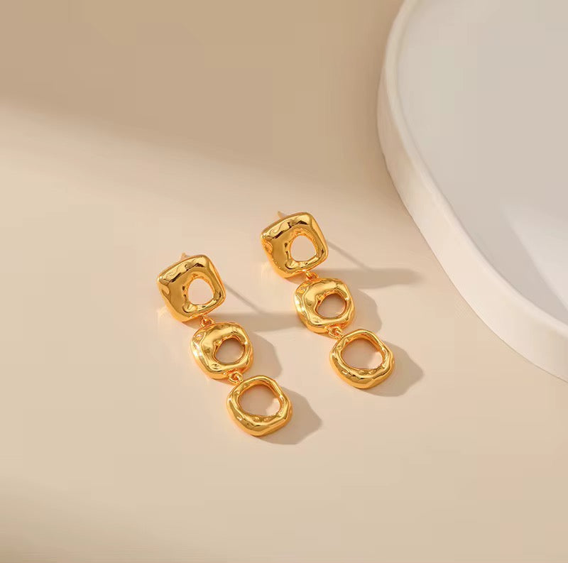 Gold earrings on a beige background