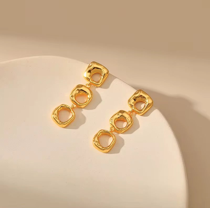 Gold earrings on a beige background