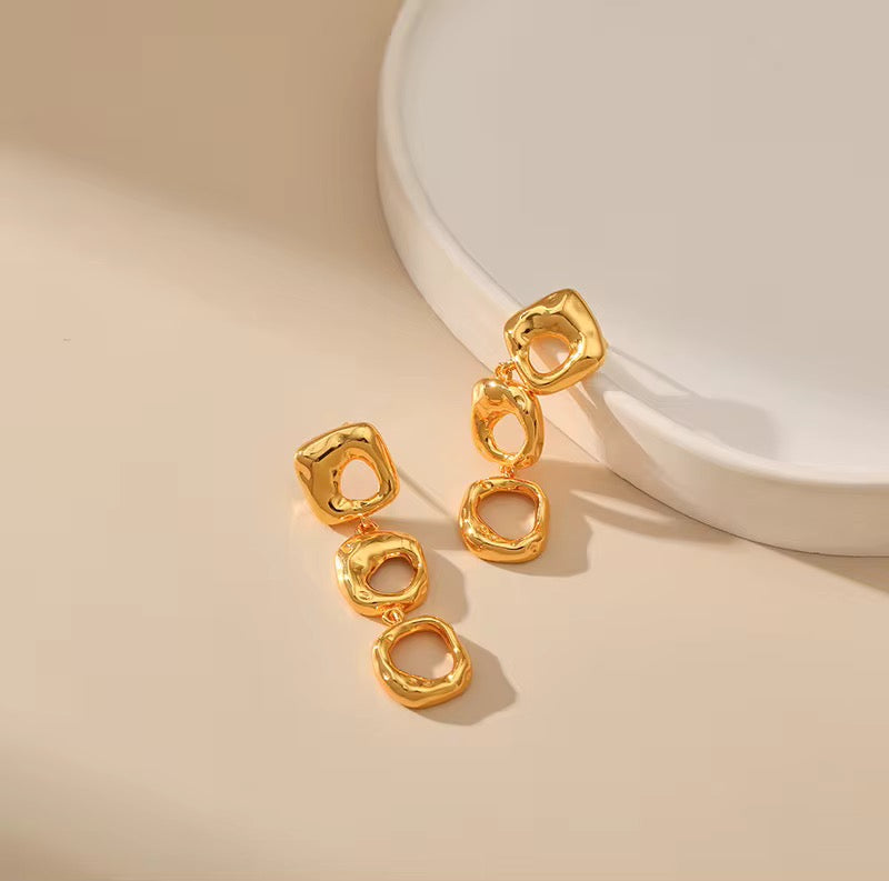 Gold earrings on a beige background