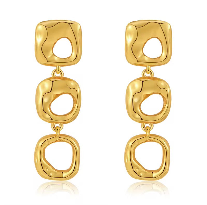 Gold earrings with square designs on a white background
