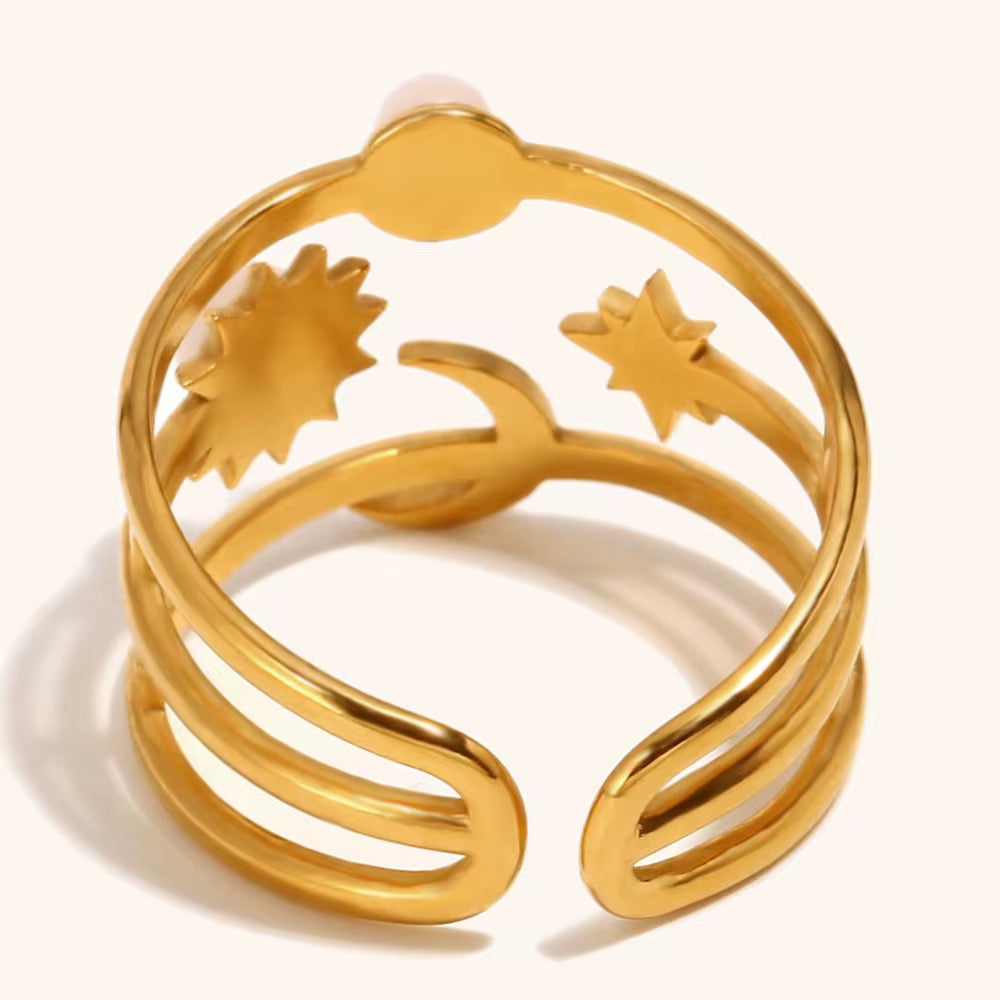 Gold ring with star and sun designs on a white background