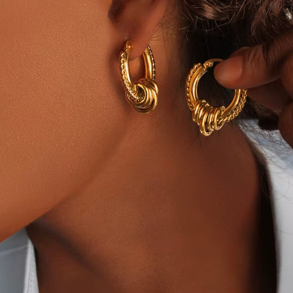 Close-up of a person wearing gold hoop earrings.