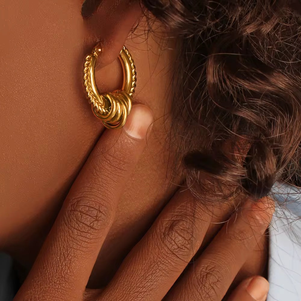 Close-up of a person wearing a gold hoop earring with braided hair.
