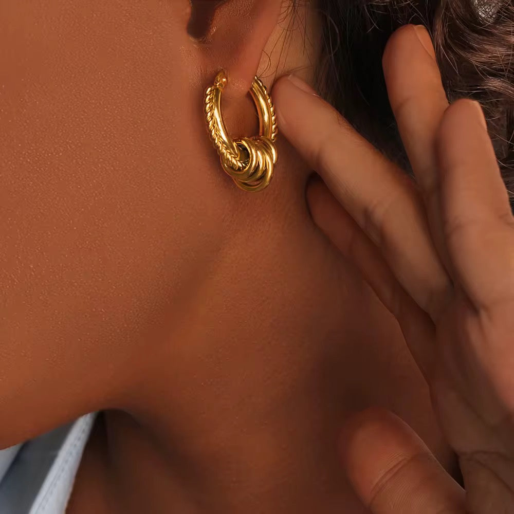 Gold hoop earring being worn on a person's ear
