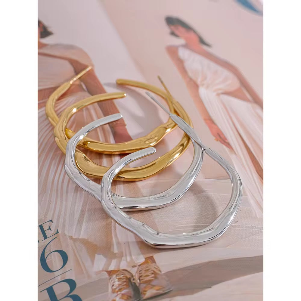 Two gold and silver hoop earrings on a magazine page.