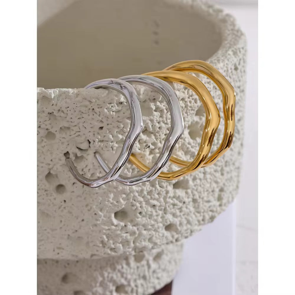Two gold and two silver rings on a textured stone surface