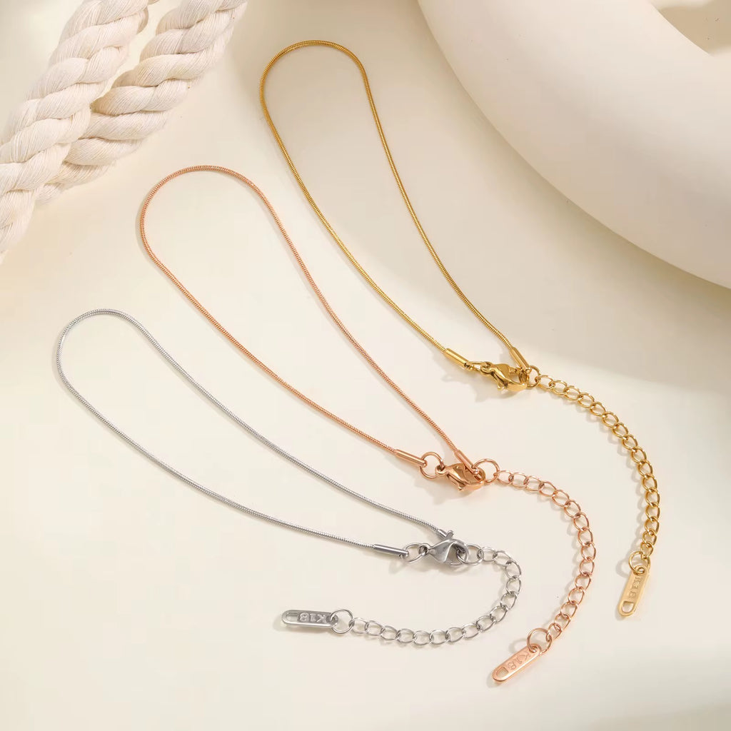 Three gold, silver, and rose gold necklaces on a light background