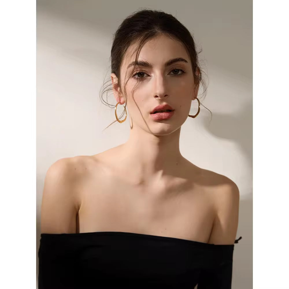 Woman wearing gold hoop earrings against a neutral background