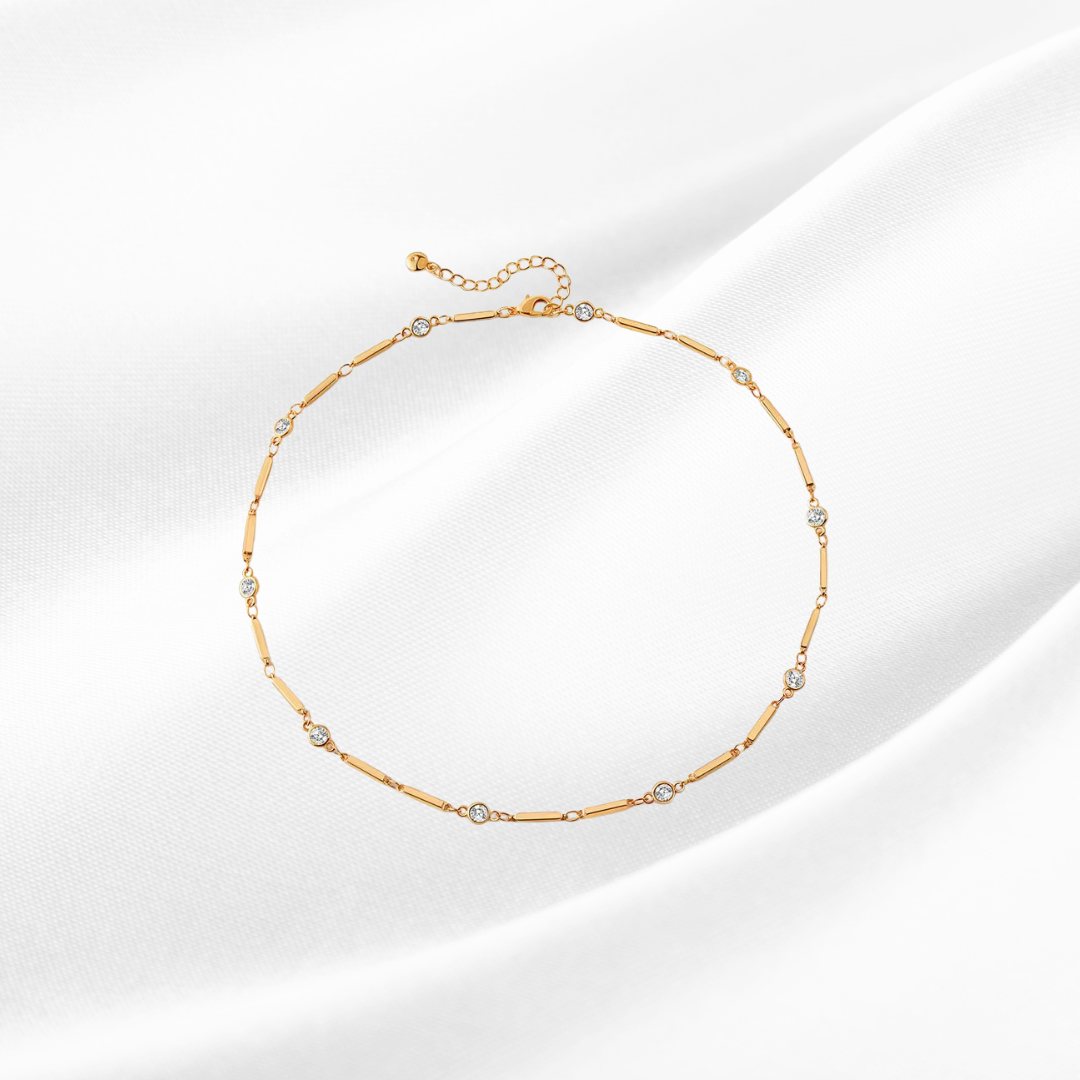 Gold necklace with small diamonds on a light background