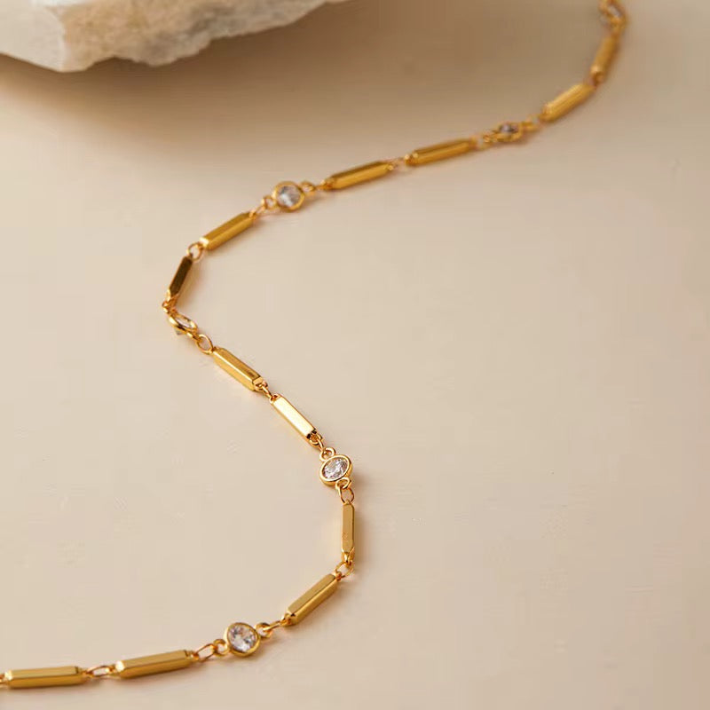 Gold necklace with small crystals on a beige background