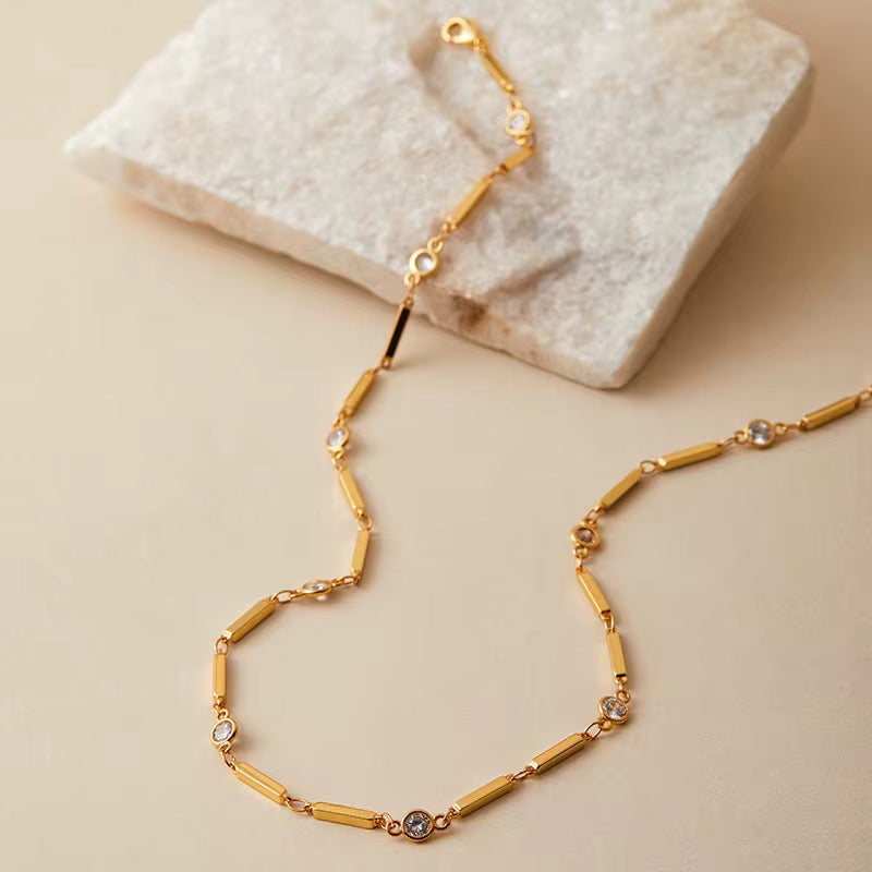 Gold necklace with small diamonds on a beige surface
