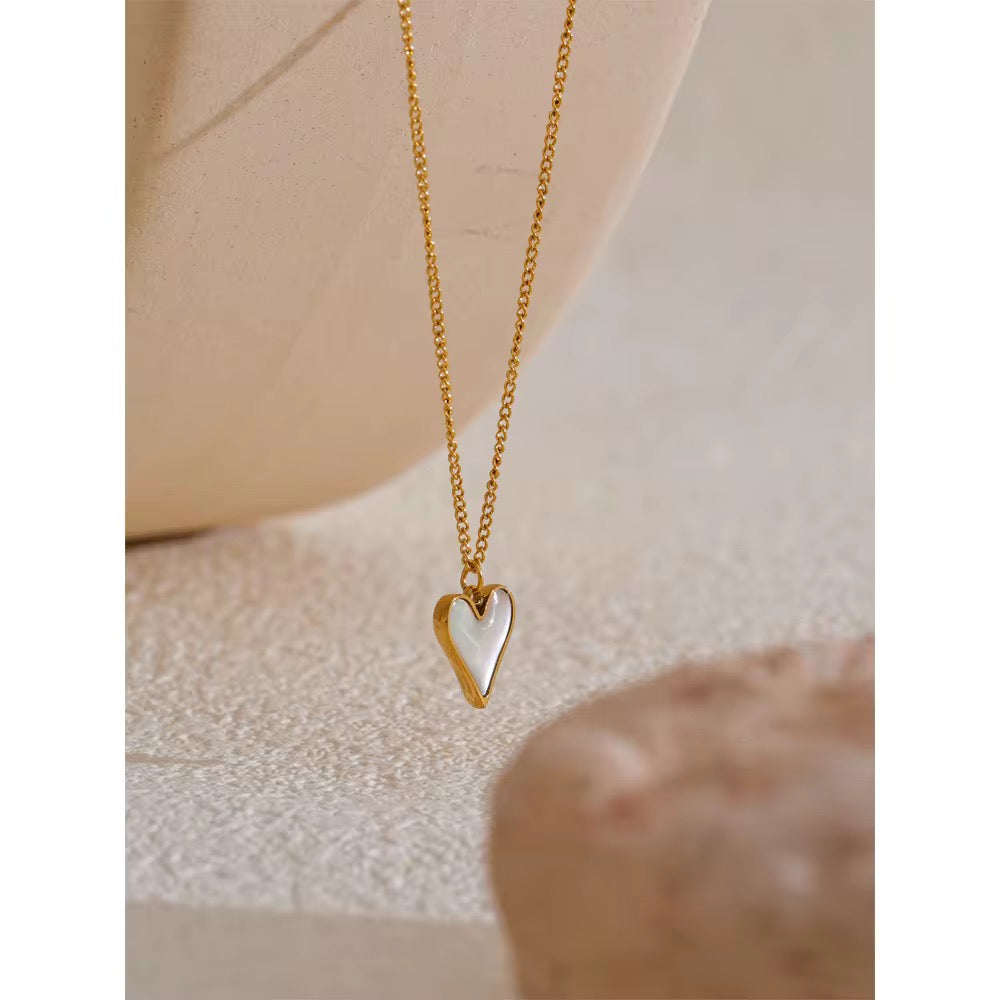 Gold heart-shaped necklace on a neutral background