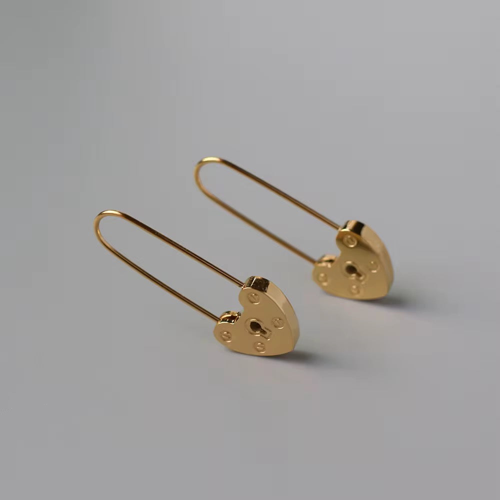 Gold heart-shaped earrings on a gray background