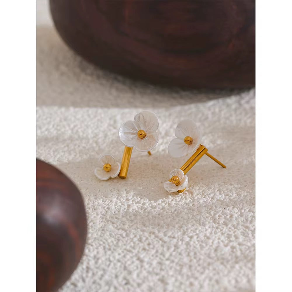 Flower-shaped earrings with gold accents on a textured surface