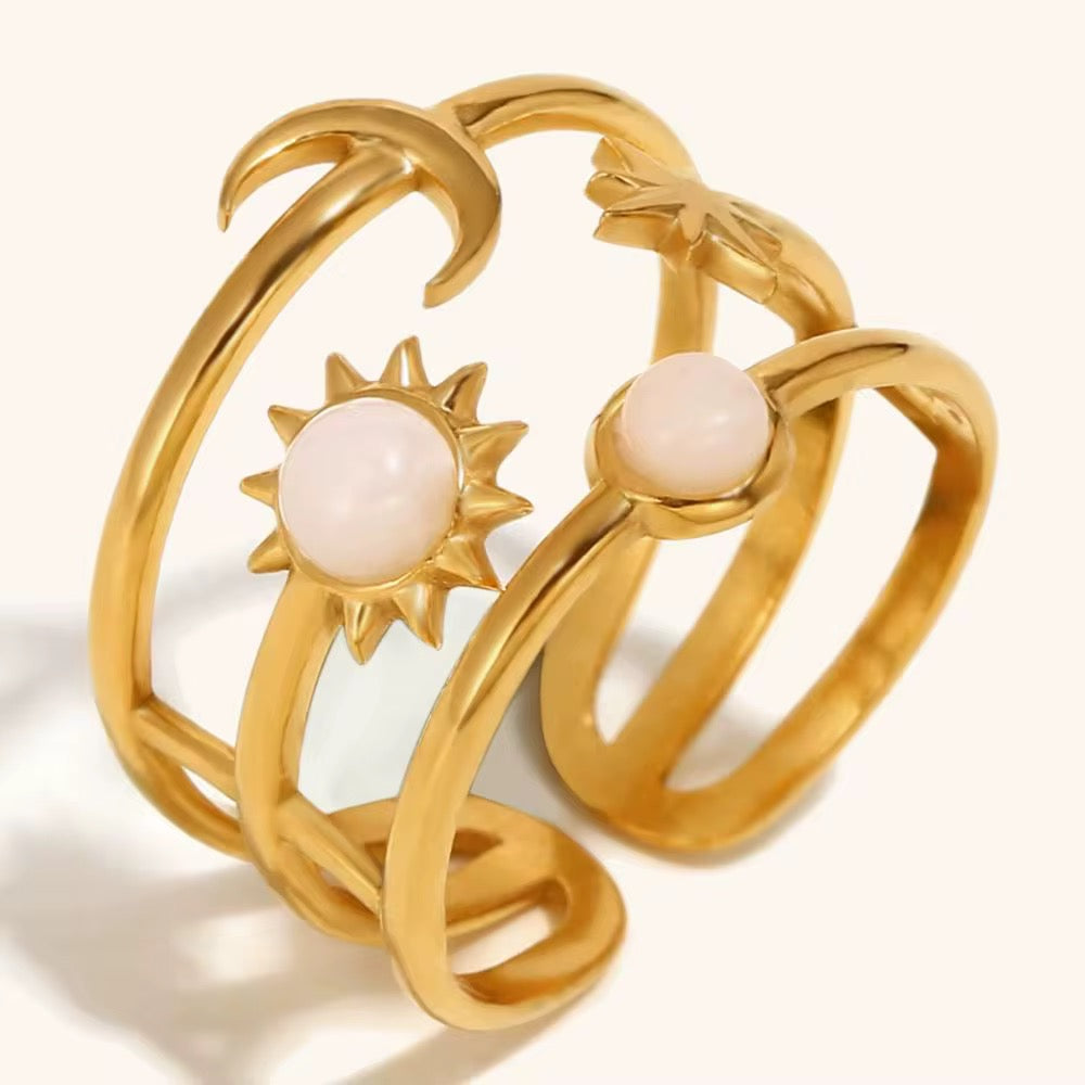 Gold ring with sun and moon designs on a white background