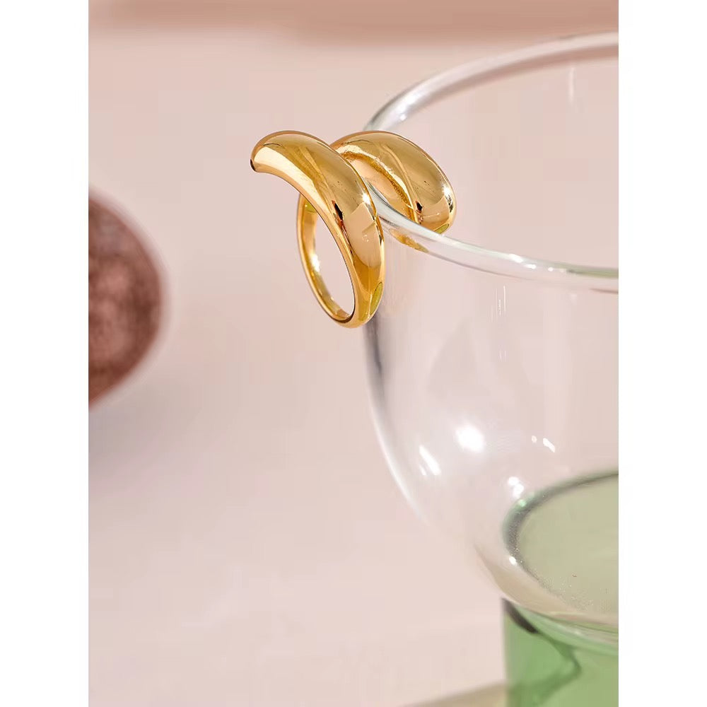 Gold ring on a clear glass object with a pink background