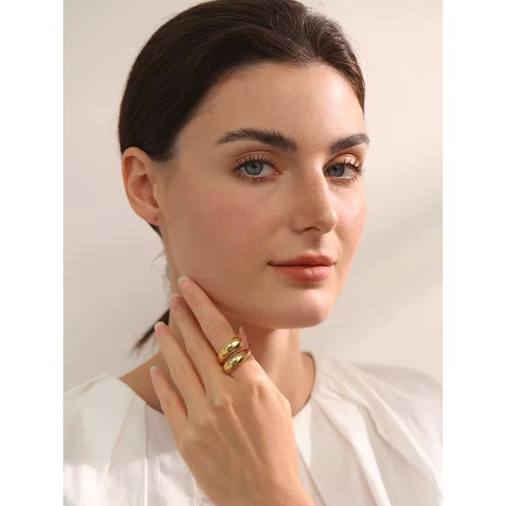 Woman wearing a gold ring on her finger against a plain background