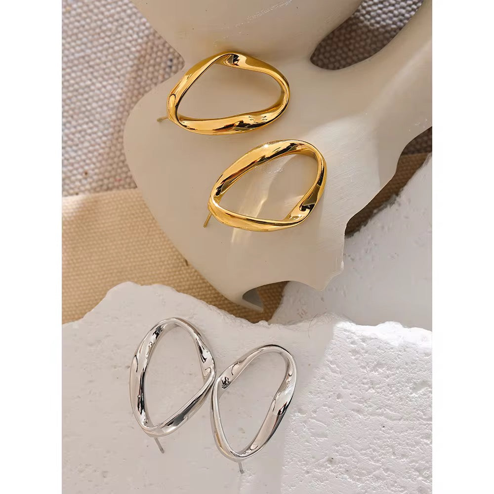 Gold and silver hoop earrings on a textured surface