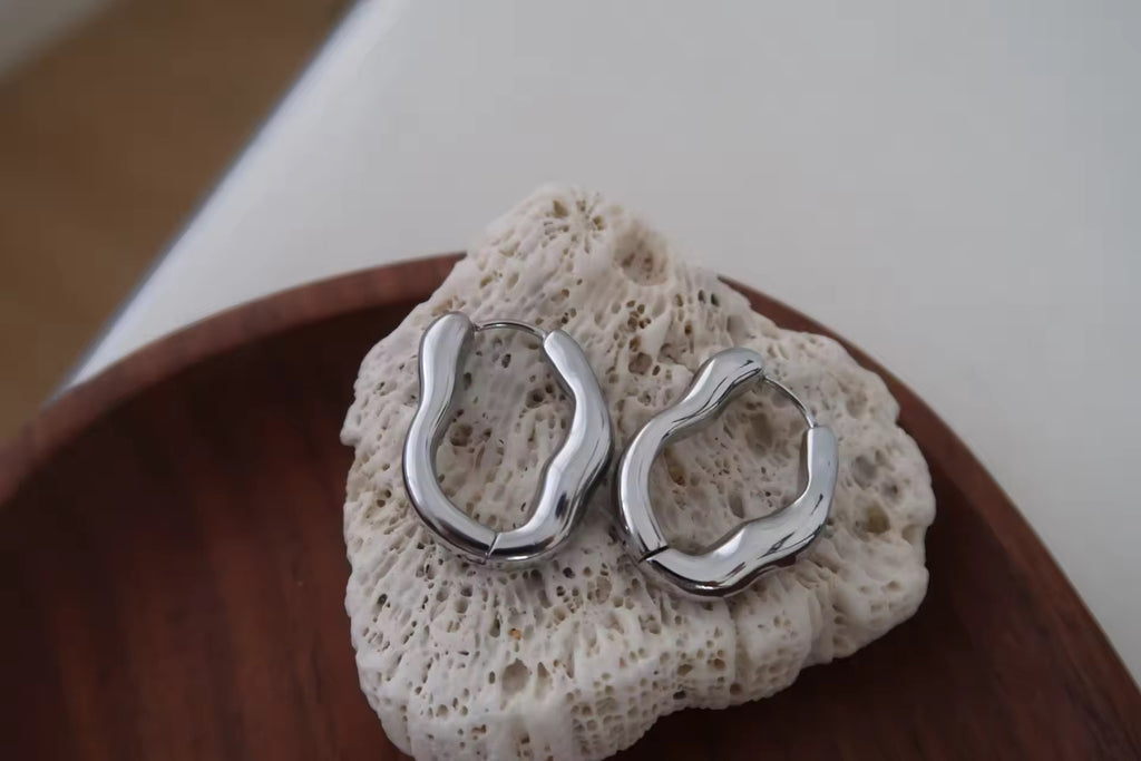 Silver hoop earrings on a piece of textured stone