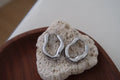 Silver hoop earrings on a piece of textured stone