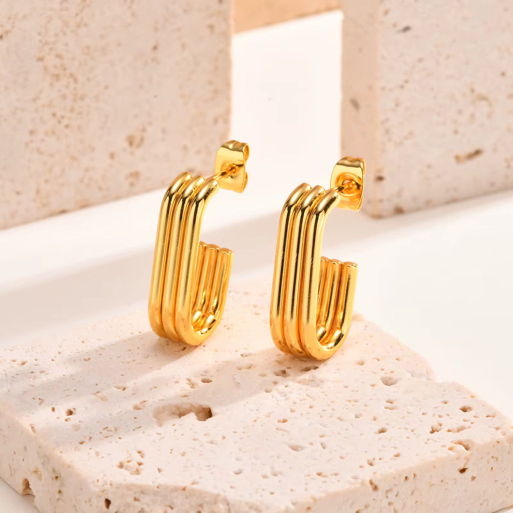 Gold hoop earrings on a textured beige surface