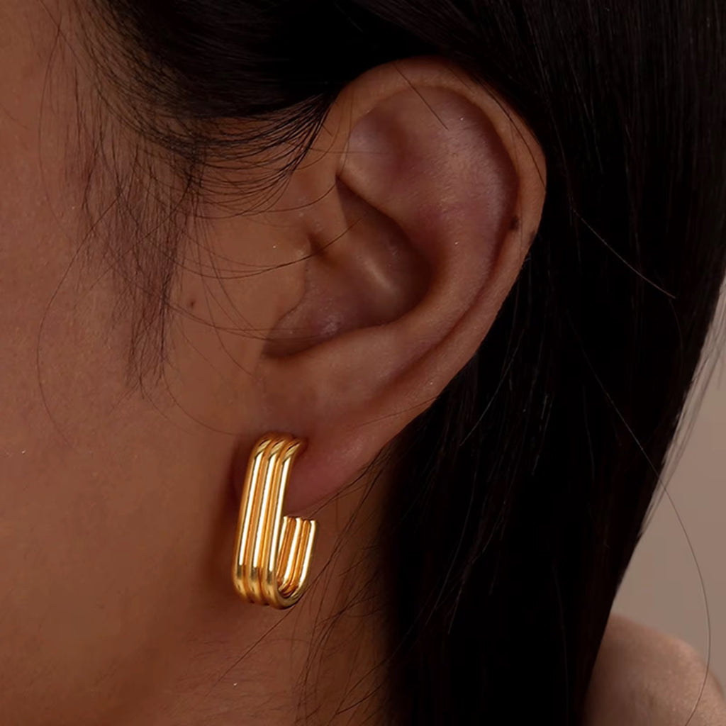 Gold hoop earrings worn by a person with dark hair.