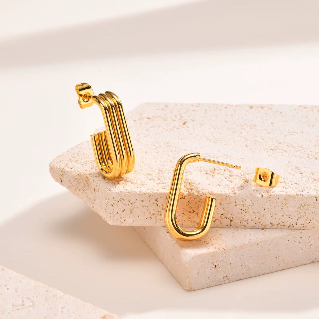 Gold hoop earrings on a beige stone surface