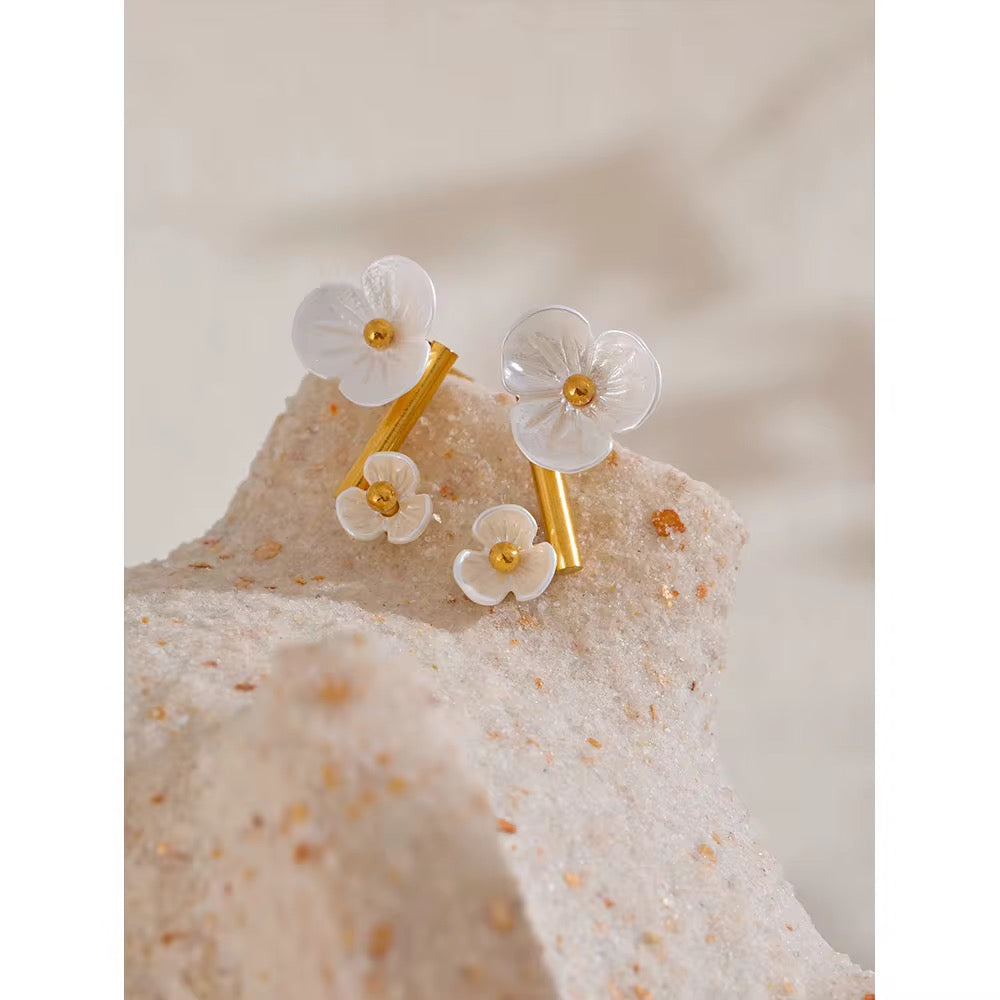 Floral earrings with gold accents on a textured beige surface