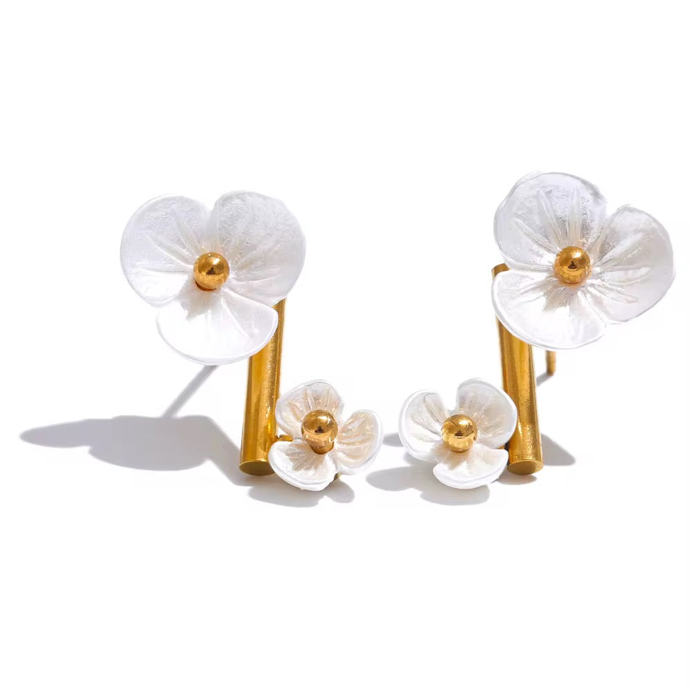 Pair of white floral earrings with gold accents on a white background