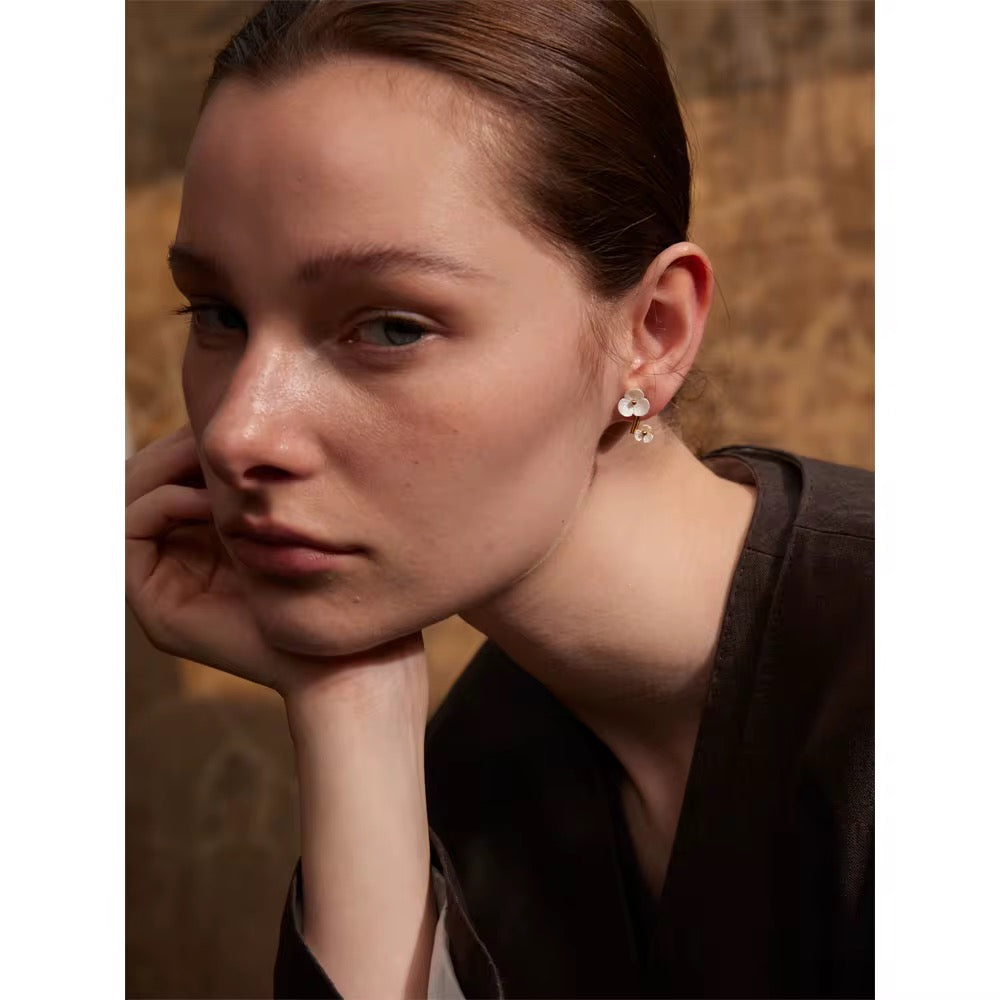 Close-up of a person wearing earrings with a neutral background